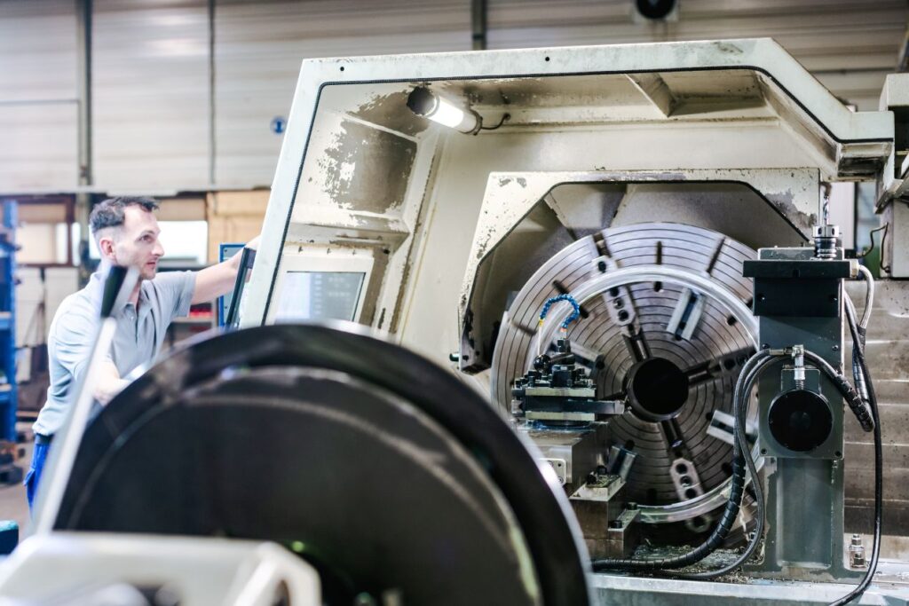 Mitarbeiter bedient CNC-Maschine im Sondermaschinenbau mit individuell gefertigter Drehvorrichtung in moderner Produktionshalle
